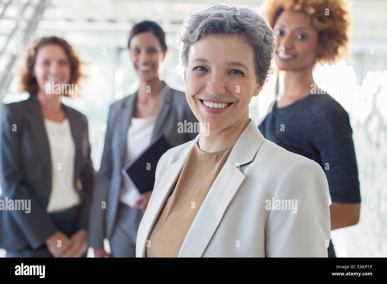 Portrait of smiling mature businesswoman with office team in background Stock Photo