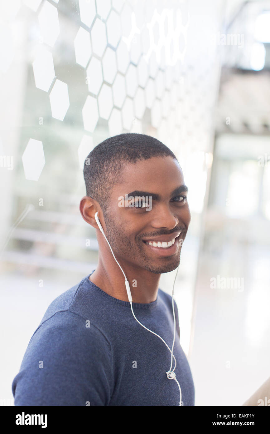 Portrait of smiling young man with earphones in office Stock Photo