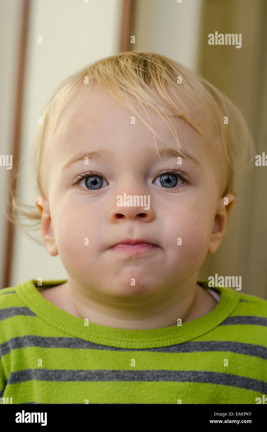 A cheeky-looking blond and blue-eyed baby boy (ca. 18 months old). Stock Photo