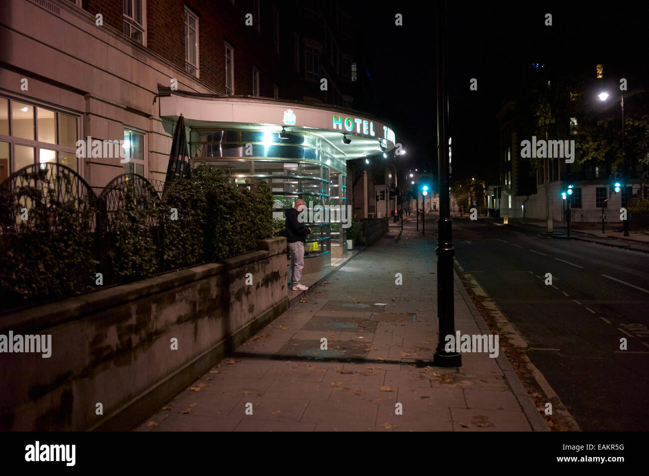 Man at night texting outside London hotel Stock Photo