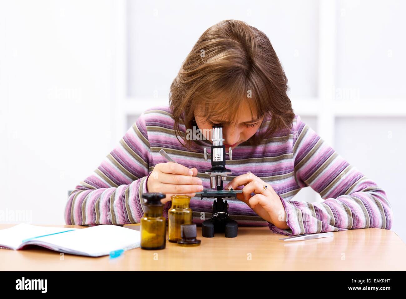 Schoolgirl looking into microscope in biology class Stock Photo - Alamy