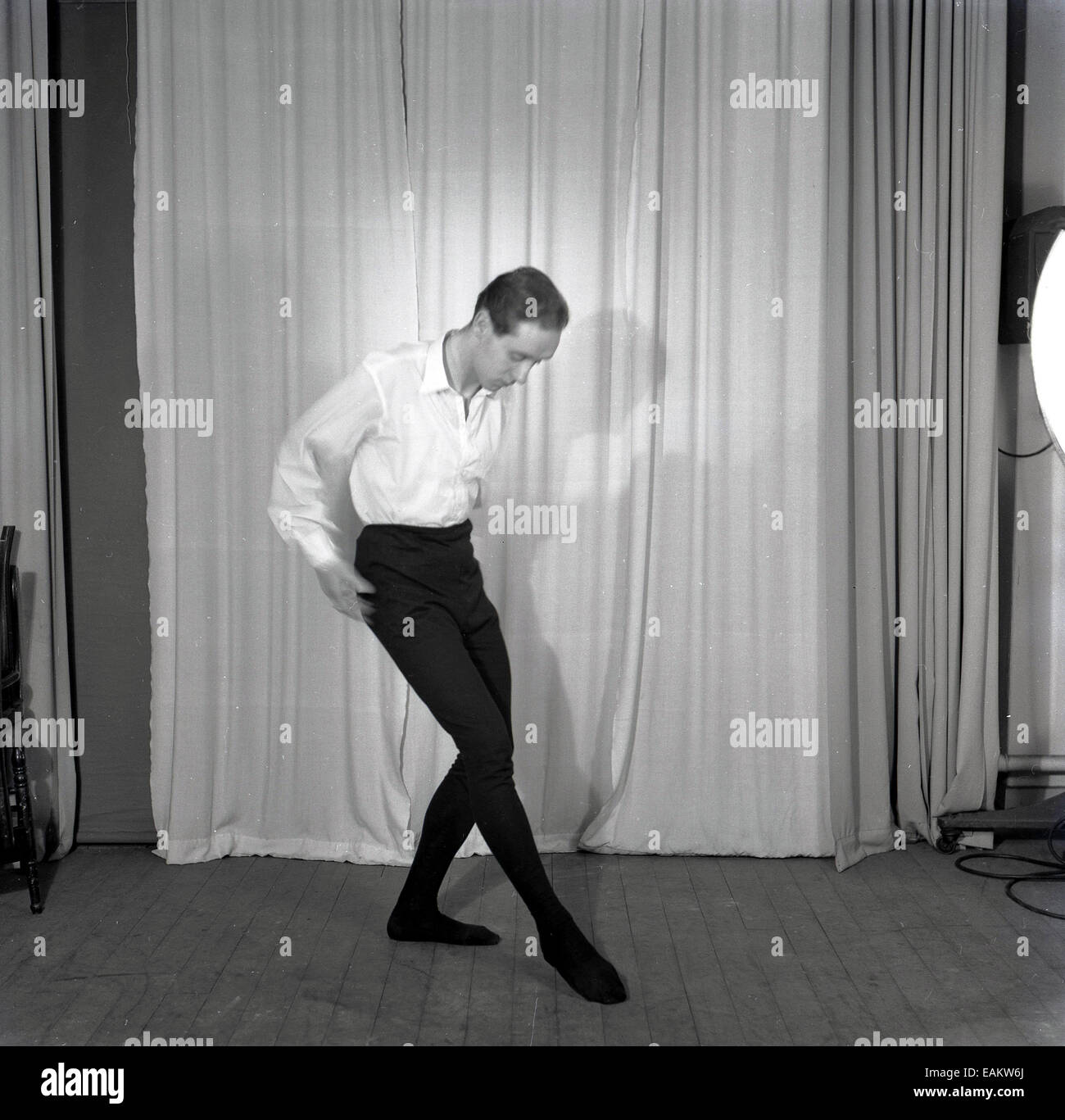1950s, historical picture of a male ballet dancer practicing or rehearsing his moves on a wooden stage floor in front of  a curtain Stock Photo
