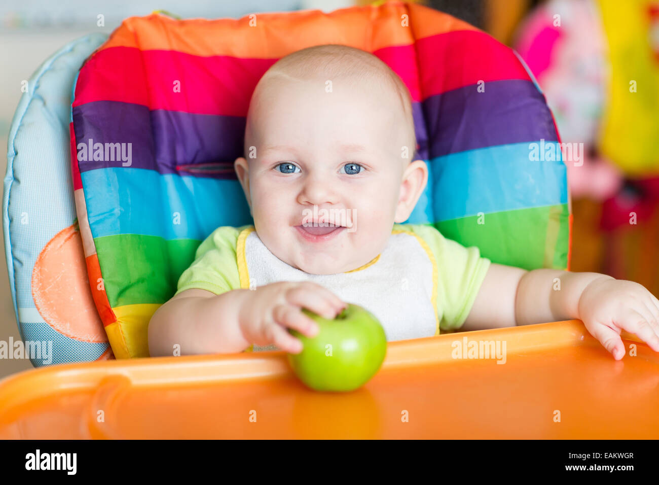 Adorable baby eating in high chair. Baby's first solid food Stock Photo