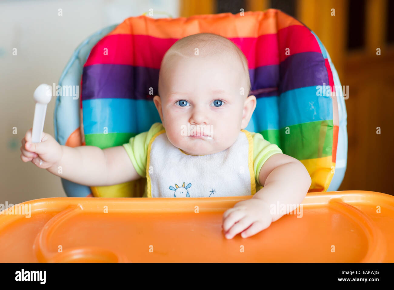 Adorable baby eating in high chair. Baby's first solid food Stock Photo