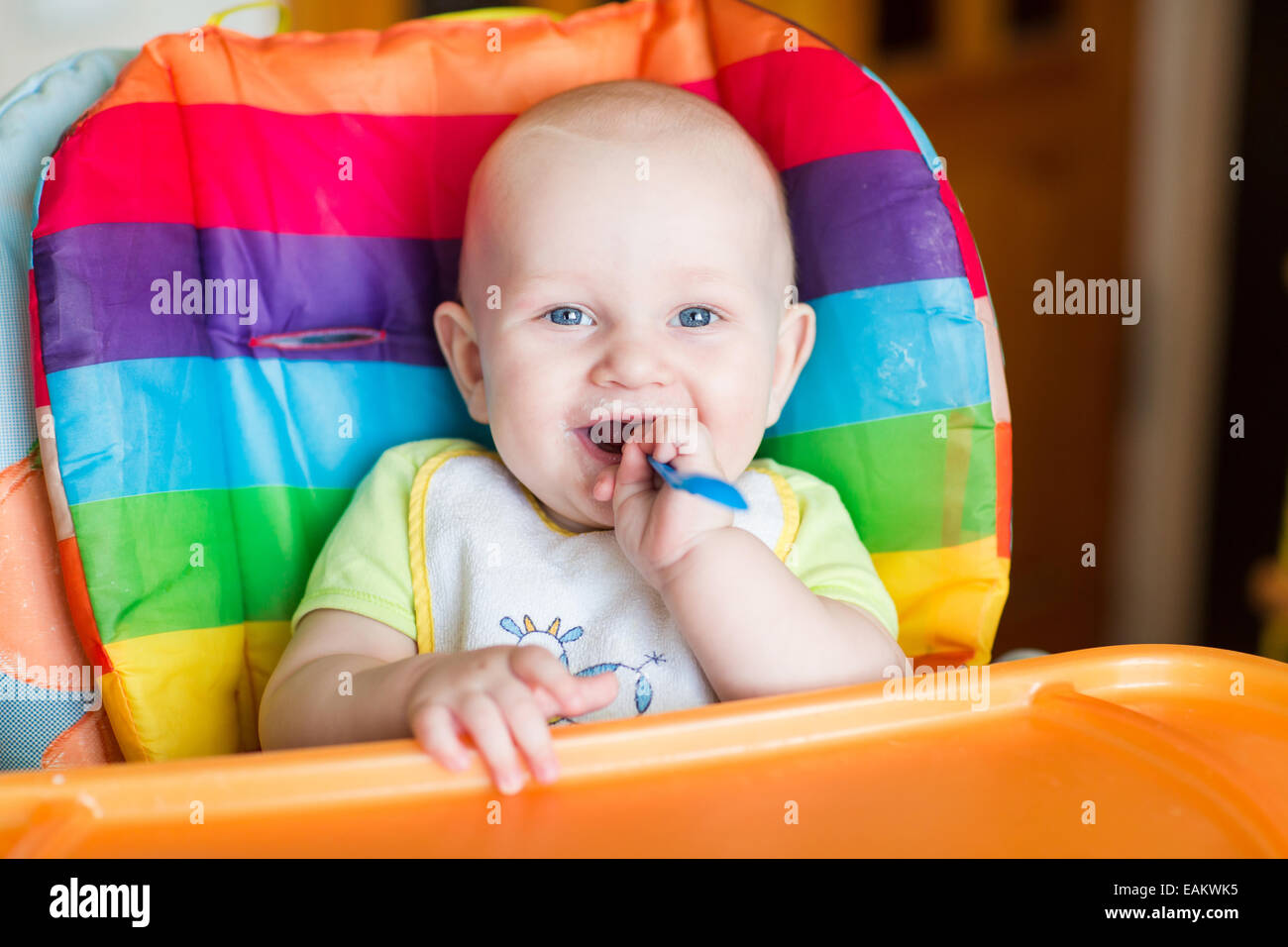 Adorable baby eating in high chair. Baby's first solid food Stock Photo