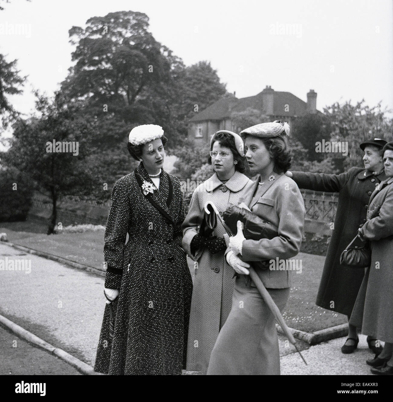 1950s, historical picture showing three attractive young ladies standing together outside, elegantly dressed in the fashions of the day, with hats, coats and handbags, England, UK. Stock Photo