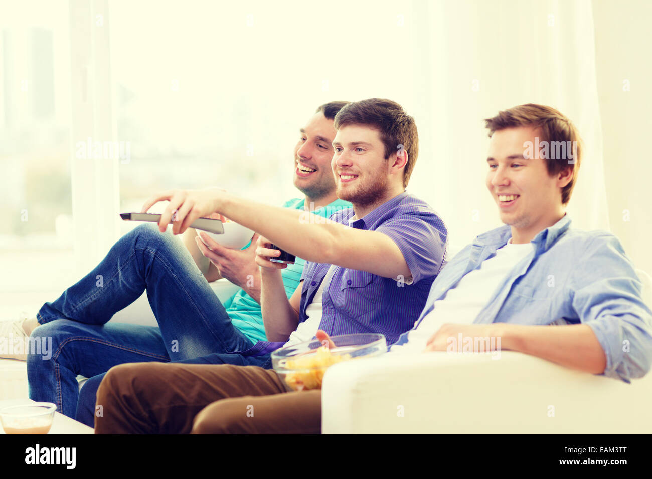 smiling friends with remote control at home Stock Photo - Alamy