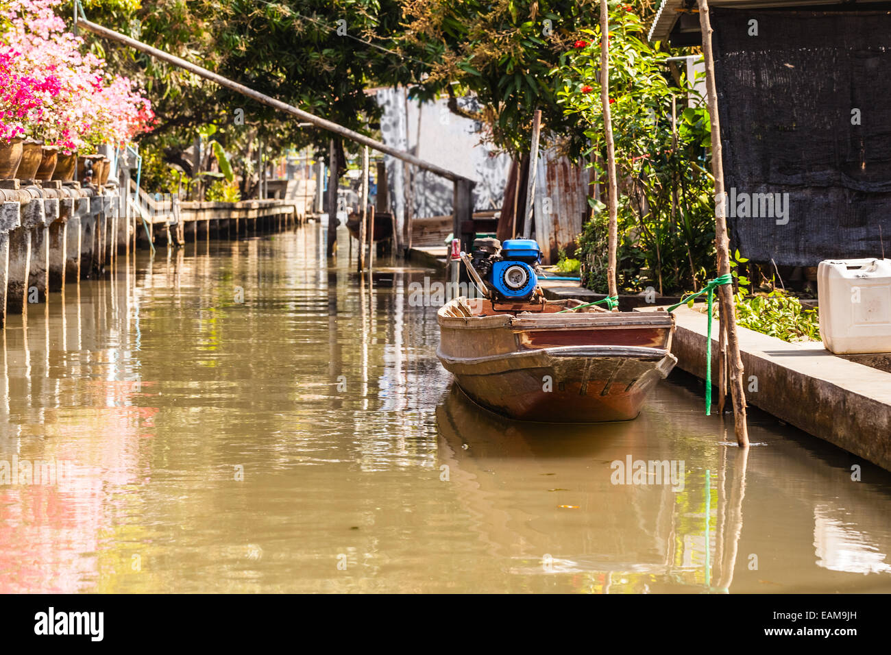 a small thai wooden motorboat in a dirty water canal Stock Photo