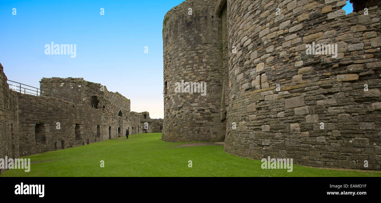 View of vast interior of historic Beaumaris castle with immense stone walls shading lawns and under blue sky in Wales Stock Photo