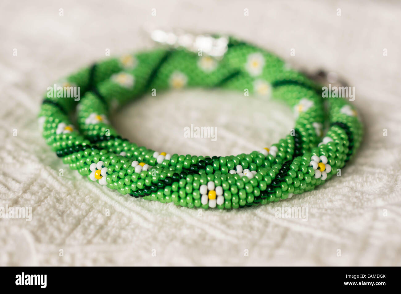Necklace from beads with flower drawing on a textile background Stock Photo