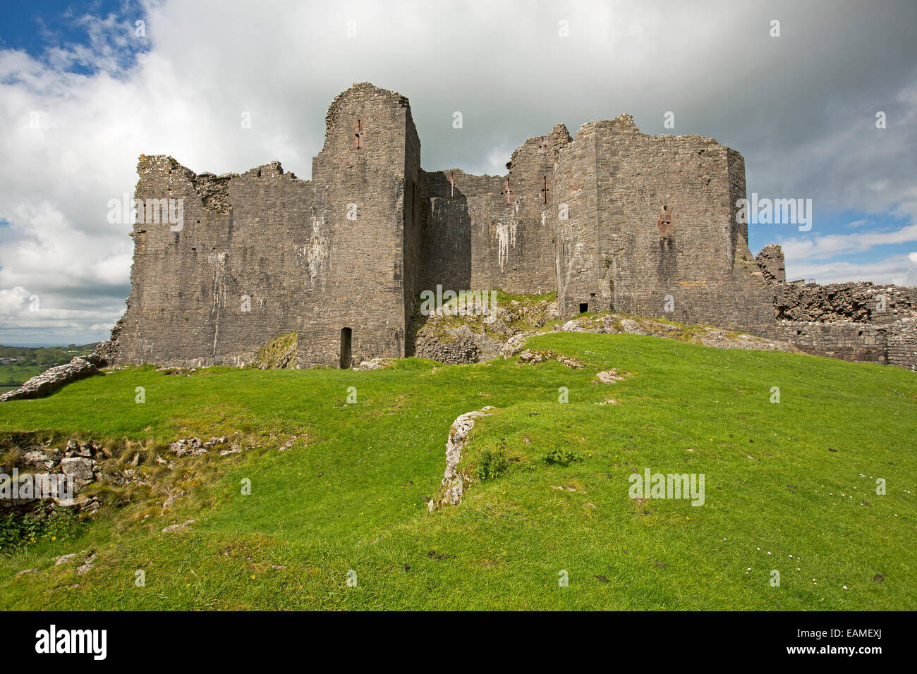 View of  spectacular ruins of 12th century Carrig Cennen castle on hilltop cloaked with emerald grass & under blue sky in Wales Stock Photo