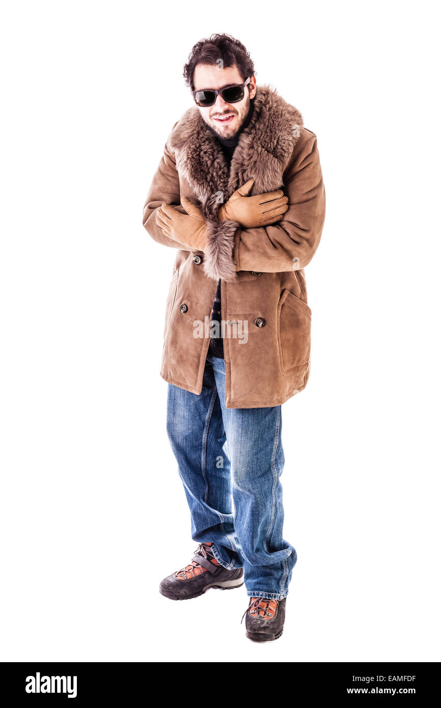 a cheerful young man wearing an expensive sheepskin furry coat isolated over a white background and shivering for the cold Stock Photo
