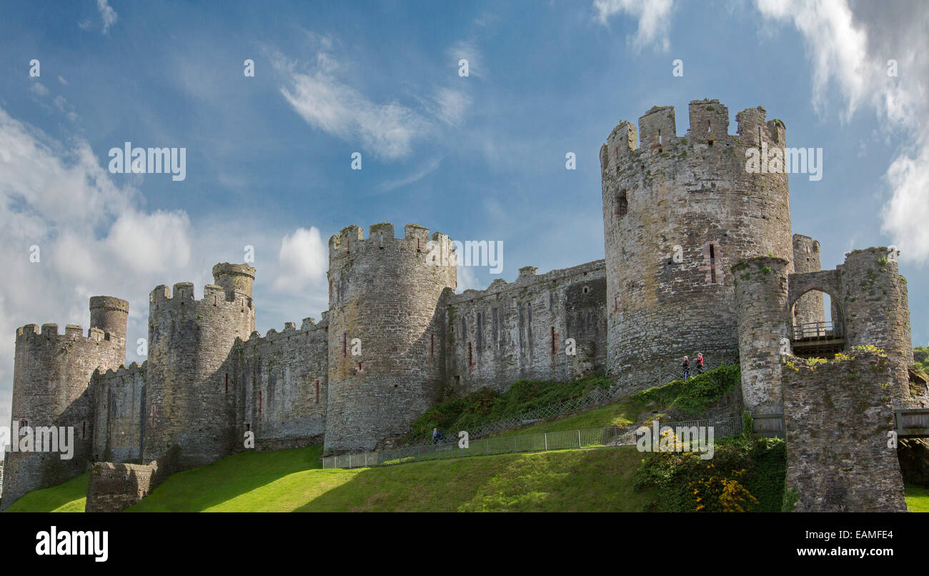 Massive relatively intact 13th century Conwy castle in Wales with huge round towers spearing into blue sky streaked with clouds Stock Photo