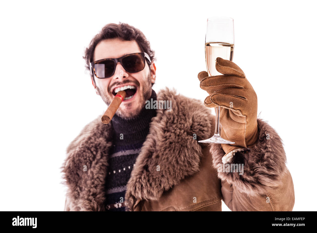 a young man wearing a sheepskin coat isolated over a white background holding a cigar and a glass with champagne Stock Photo