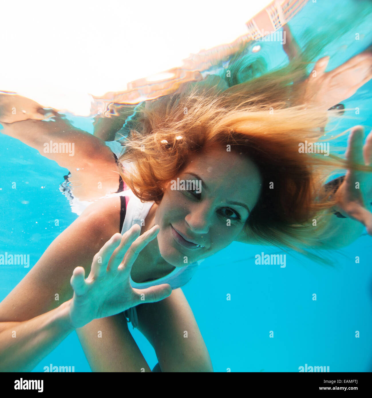 Attractive female with eyes open looking and smiling while underwater