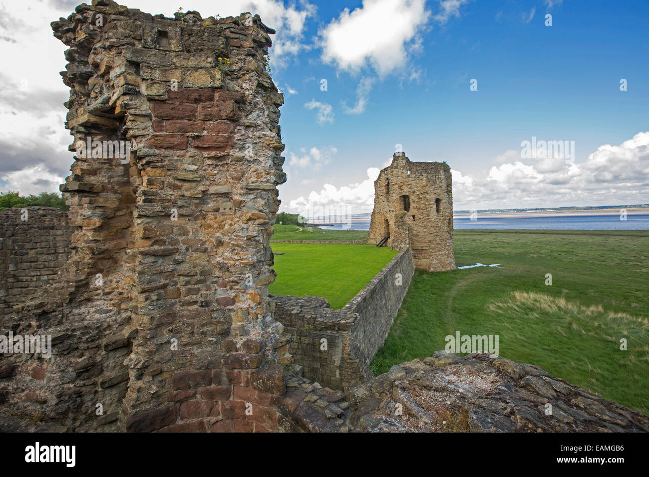 Ruins of 13th century Flint castle on edge of  River Dee estuary under blue sky daubed with clouds in northern Wales Stock Photo