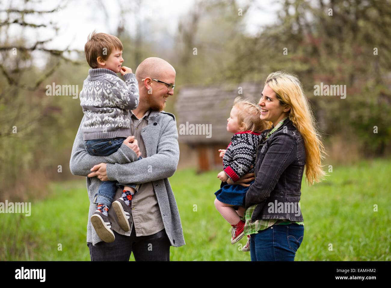 Lifestyle portrait of a family of four including a mother, father, son, and daughter interacting showing happiness. Stock Photo