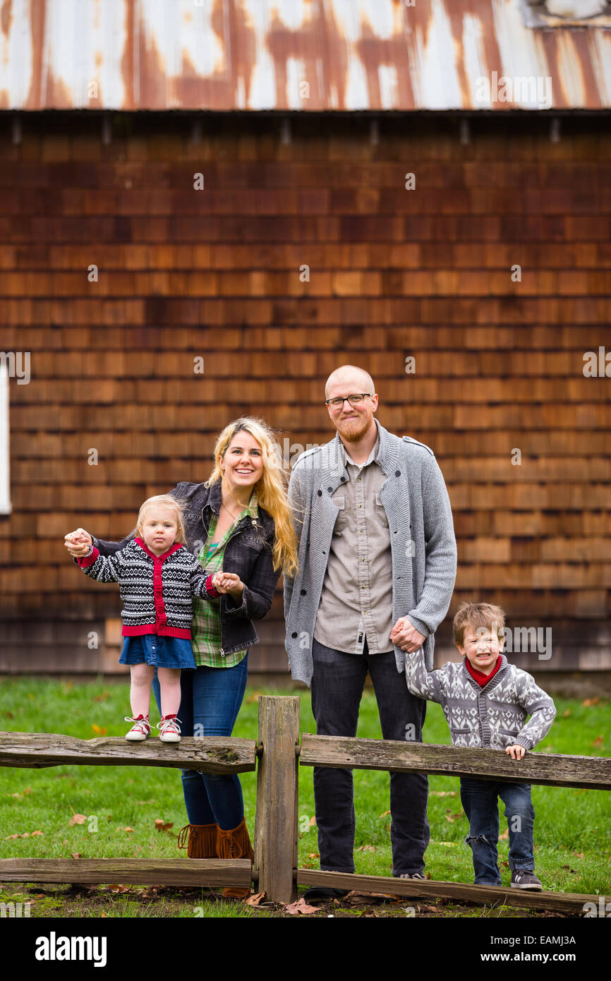 Family lifestyle portrait of a mother, father, son and daughter in front of a rustic barn in the country. Stock Photo