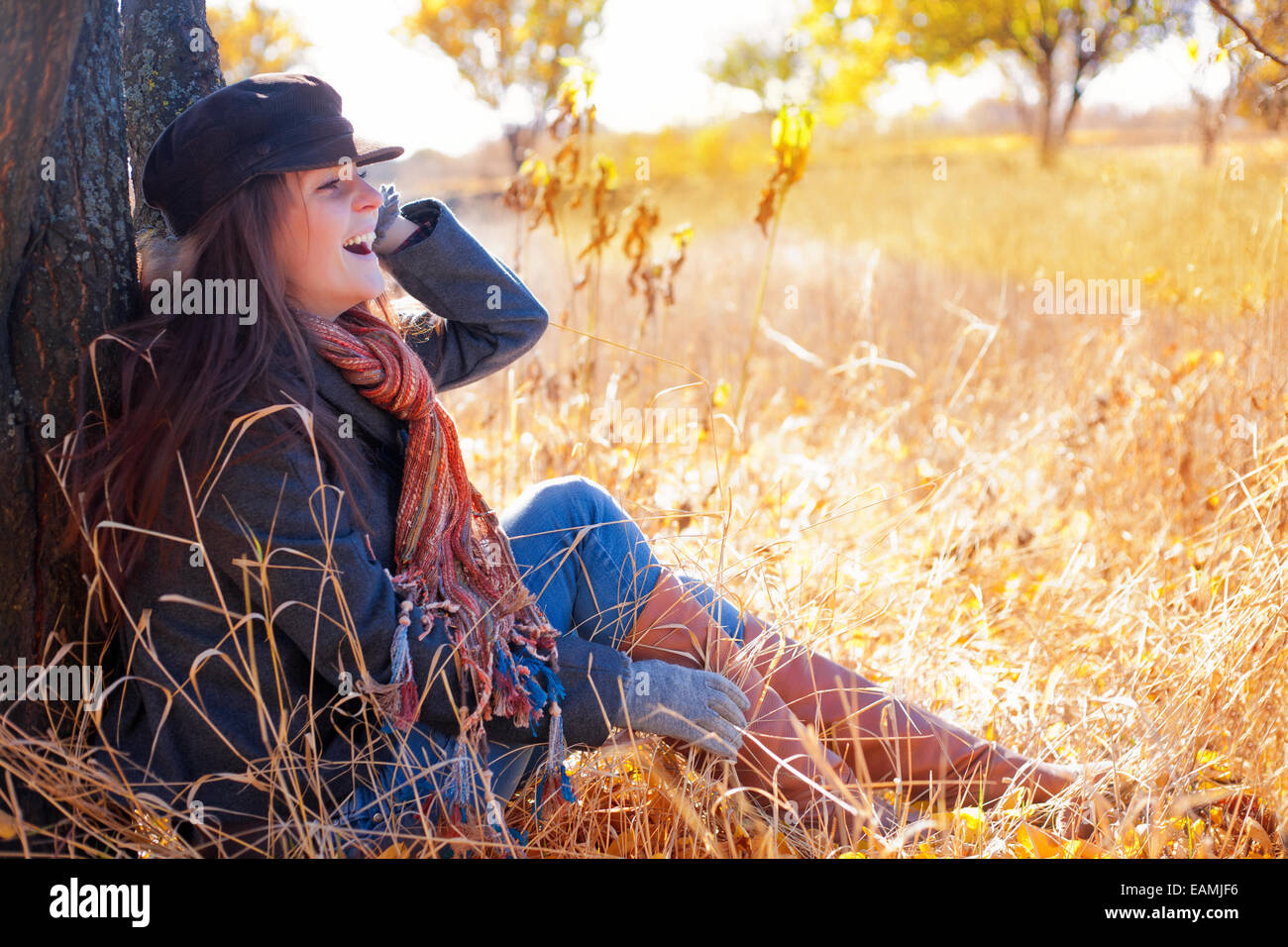 Girl sitting near a tree in autumn Stock Photo