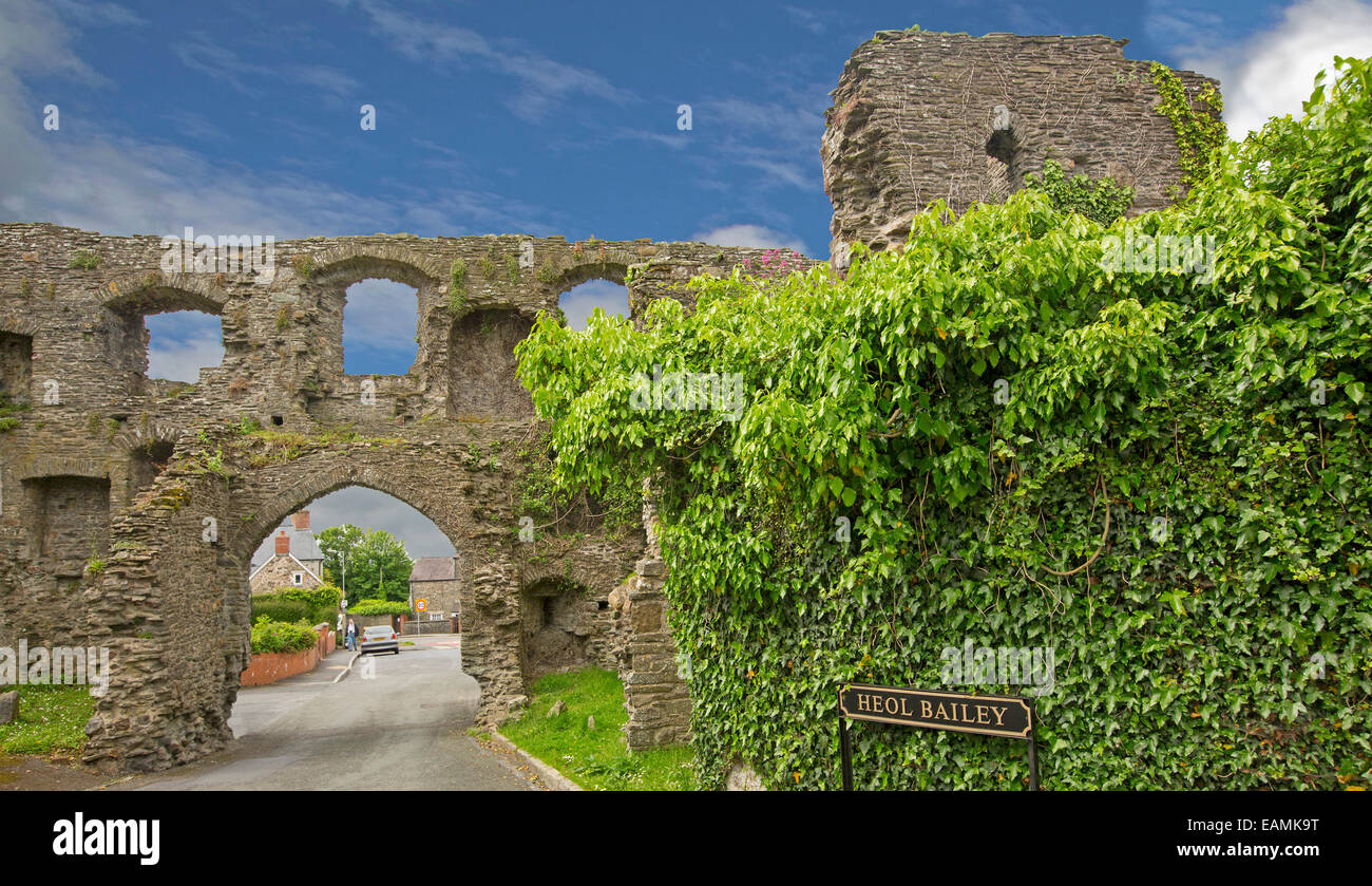 Ruins of old gatehouse of Kidwelly castle with glimpse of modern village beyond high archway rising to blue sky Stock Photo