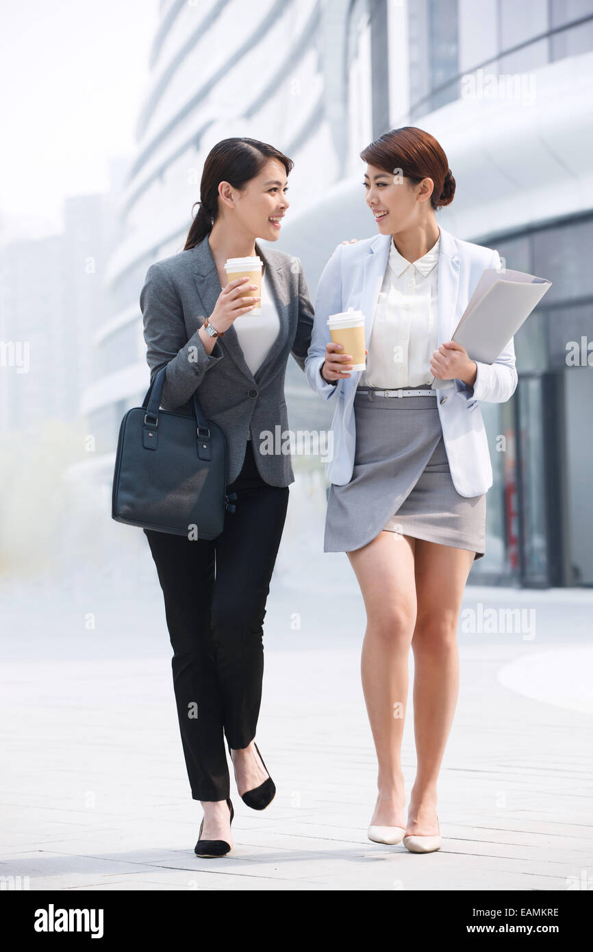 Two business lady holding a coffee cup on the way to work Stock Photo