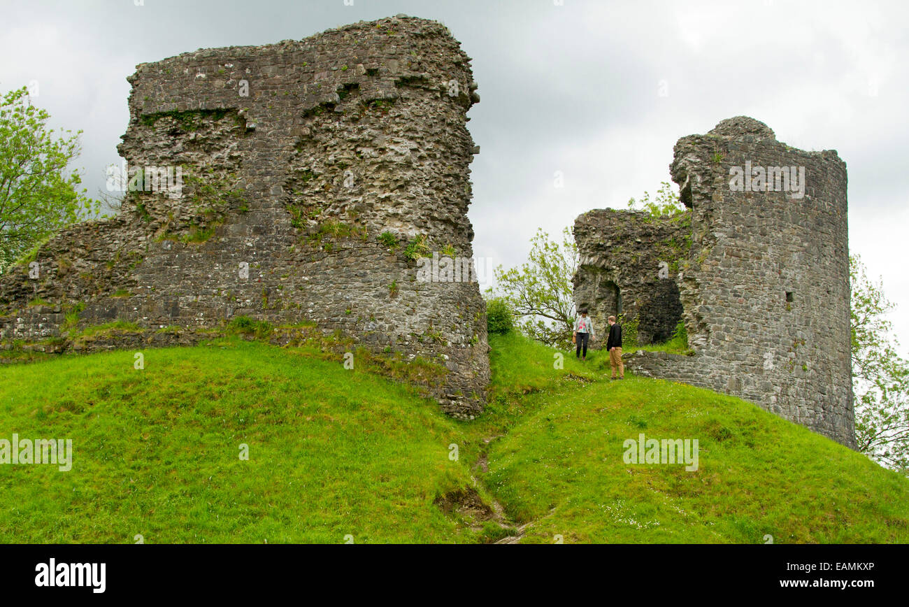 Remains of 12th century castle on grassy hilltop at village of Llandovery, Wales with two people standing by ancient stone walls Stock Photo