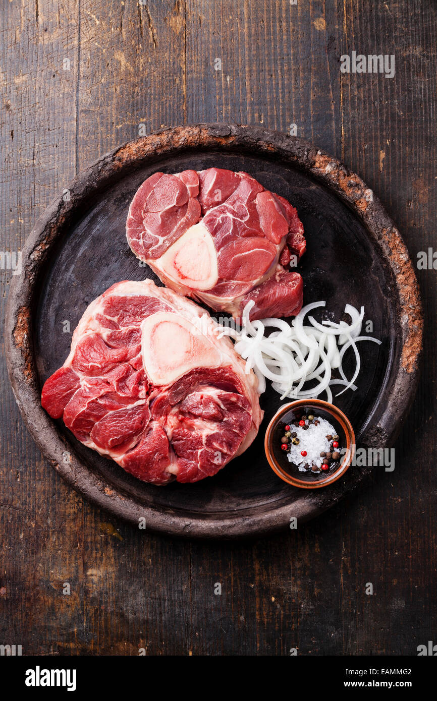 Raw fresh cross cut veal shank and Ingredients for making Osso Buco on dark wooden background Stock Photo