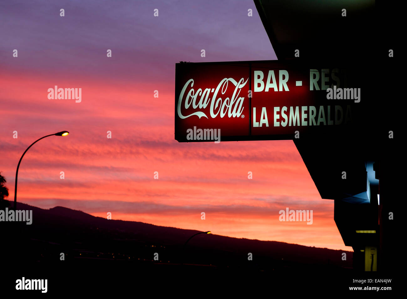 Red sky at dawn with Coca Cola sign on the Bar La Esmeralda, Playa San Juan, Tenerife, Canary Islands, Spain. Stock Photo