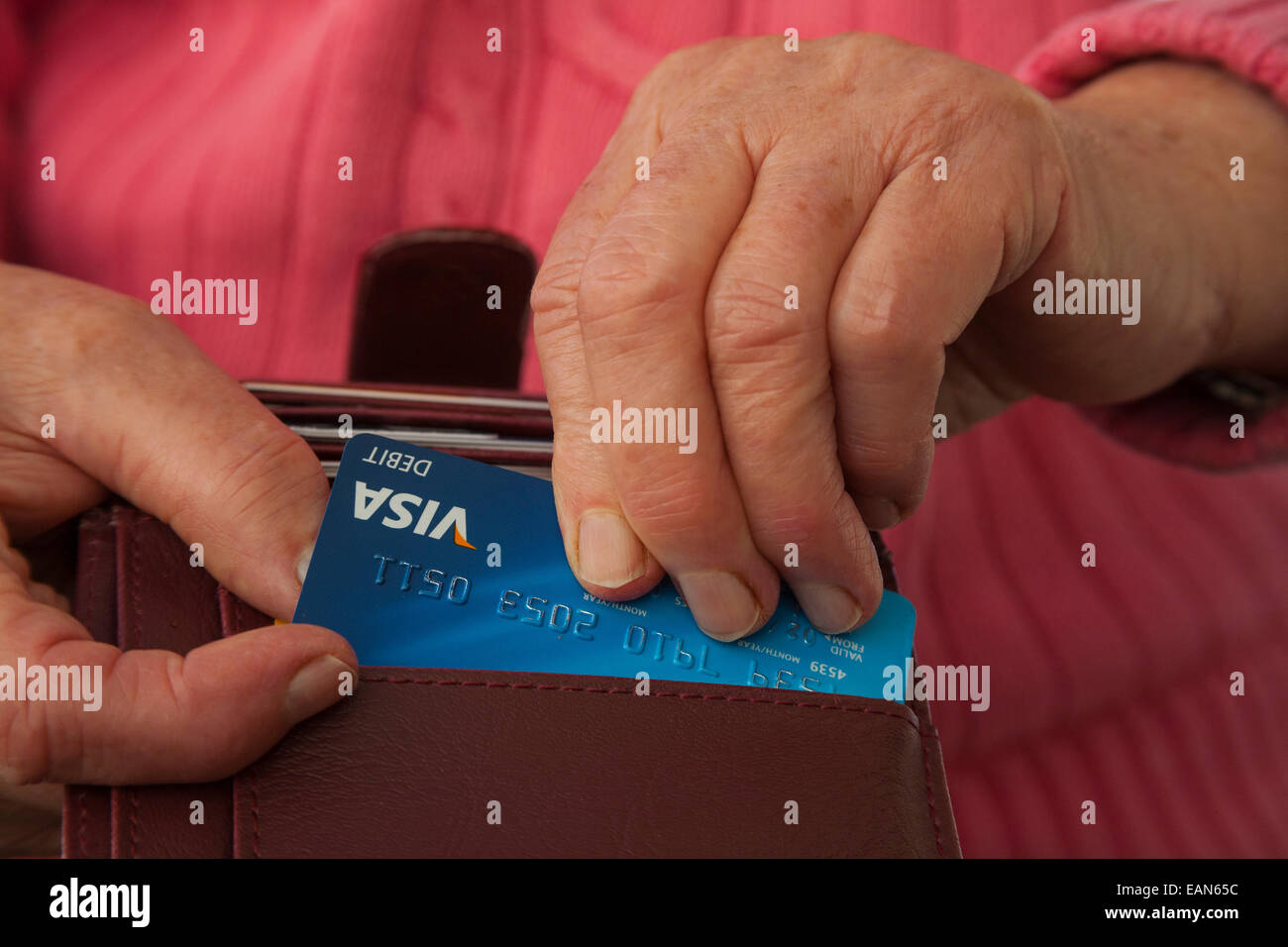 Elderly woman taking a Visa debit card out of a wallet to make a card purchase Stock Photo