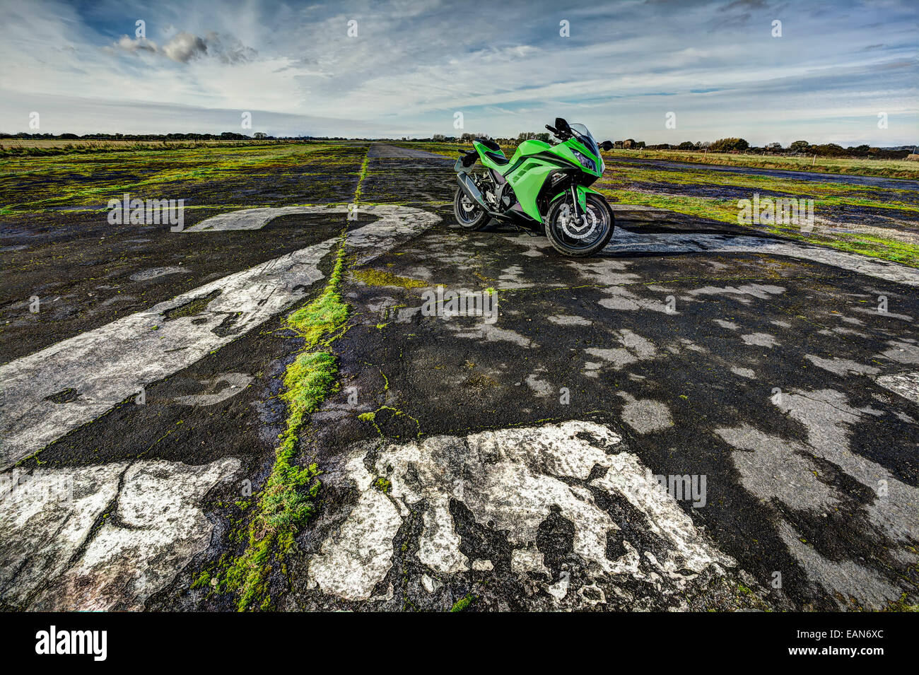 Green sports motorcycle parked on disused airfield runway Stock Photo