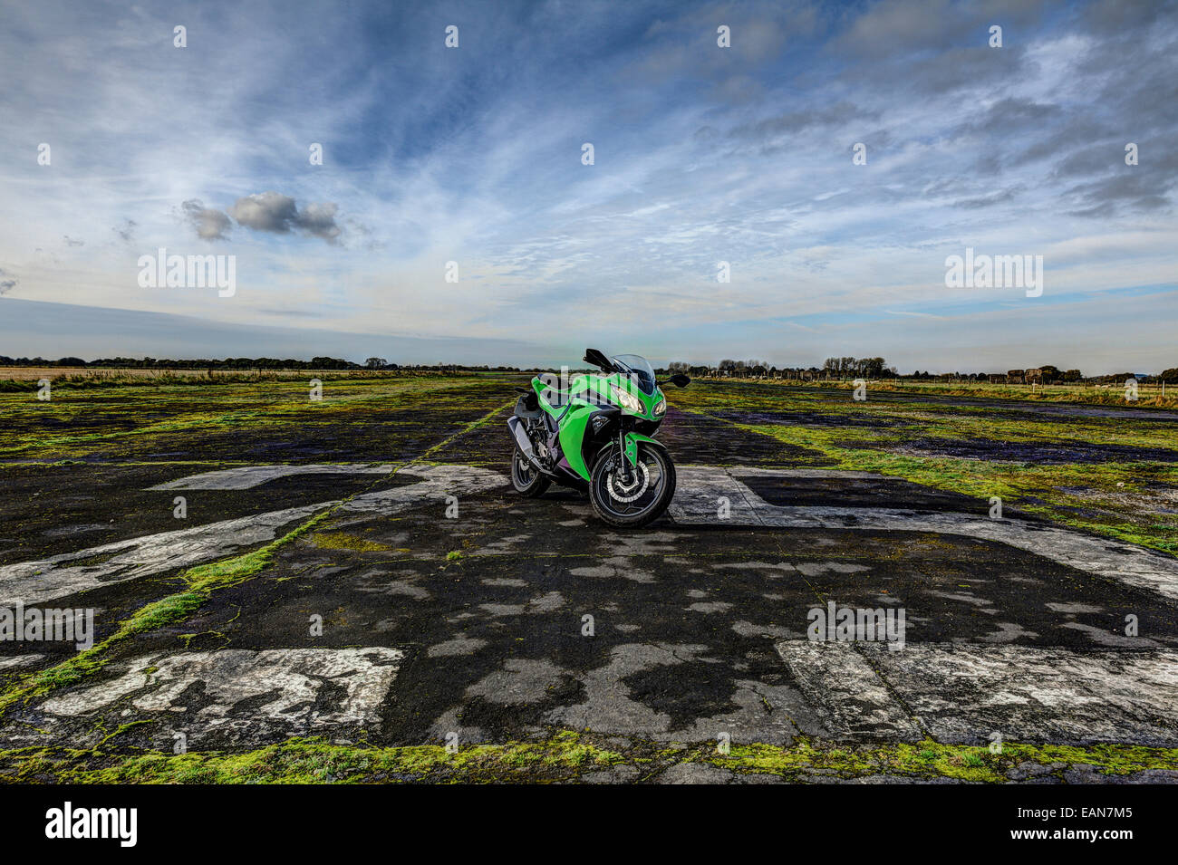 Green sports motorcycle parked on disused airfield runway Stock Photo