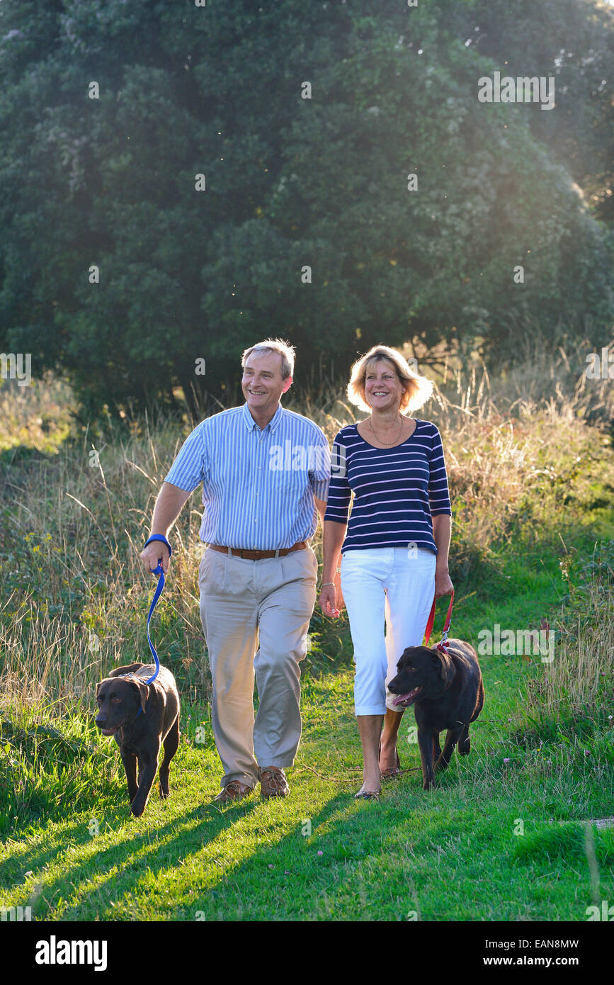 A mature couple walking their dogs on the South Downs, Eastbourne. East Sussex, UK Stock Photo