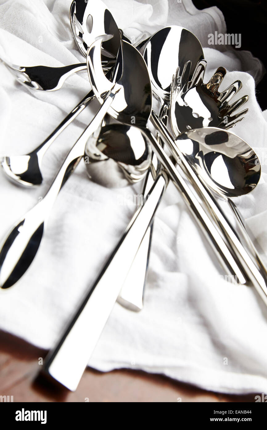 silver serving set over a white napkin on a wooden table drastic angle Stock Photo