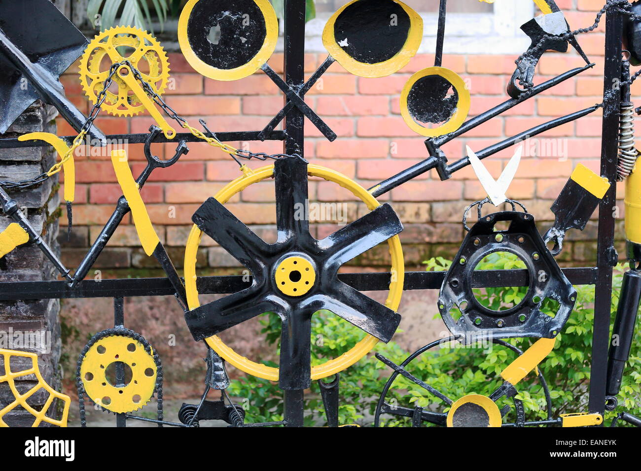 Black and yellow painted bicycle parts and old tools screwed to a metallic door of a restaurant in a street of Pokhara city-Kask Stock Photo