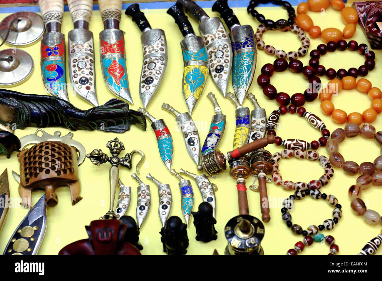 Display of nepalese handicrafts -khukuri gurkha daggers-bead bracelets-buddhist prayer wheels-small hand cymbals- in windowshop Stock Photo