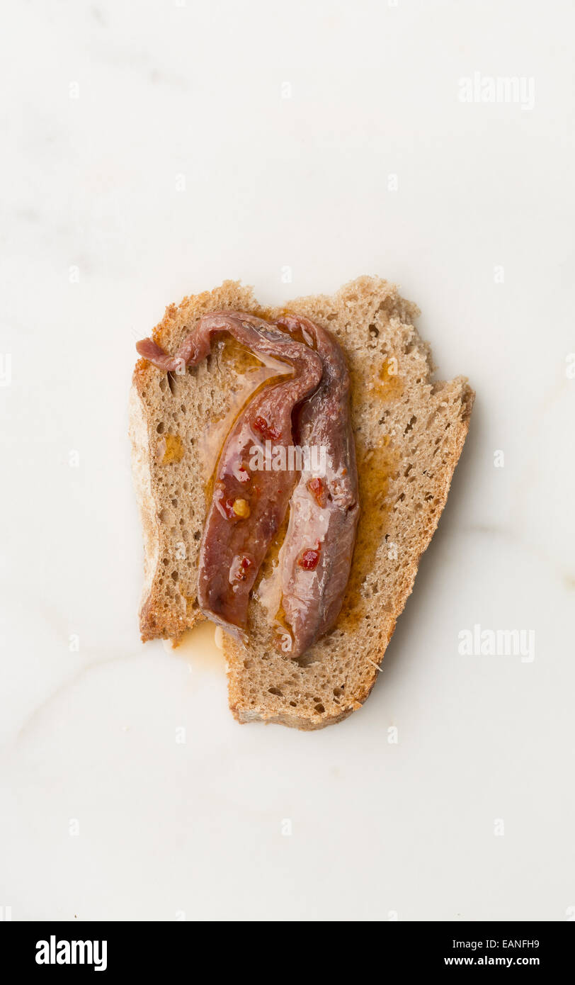 anchovies fillets with chilli pepper and oil on a slice of rye bread Stock Photo