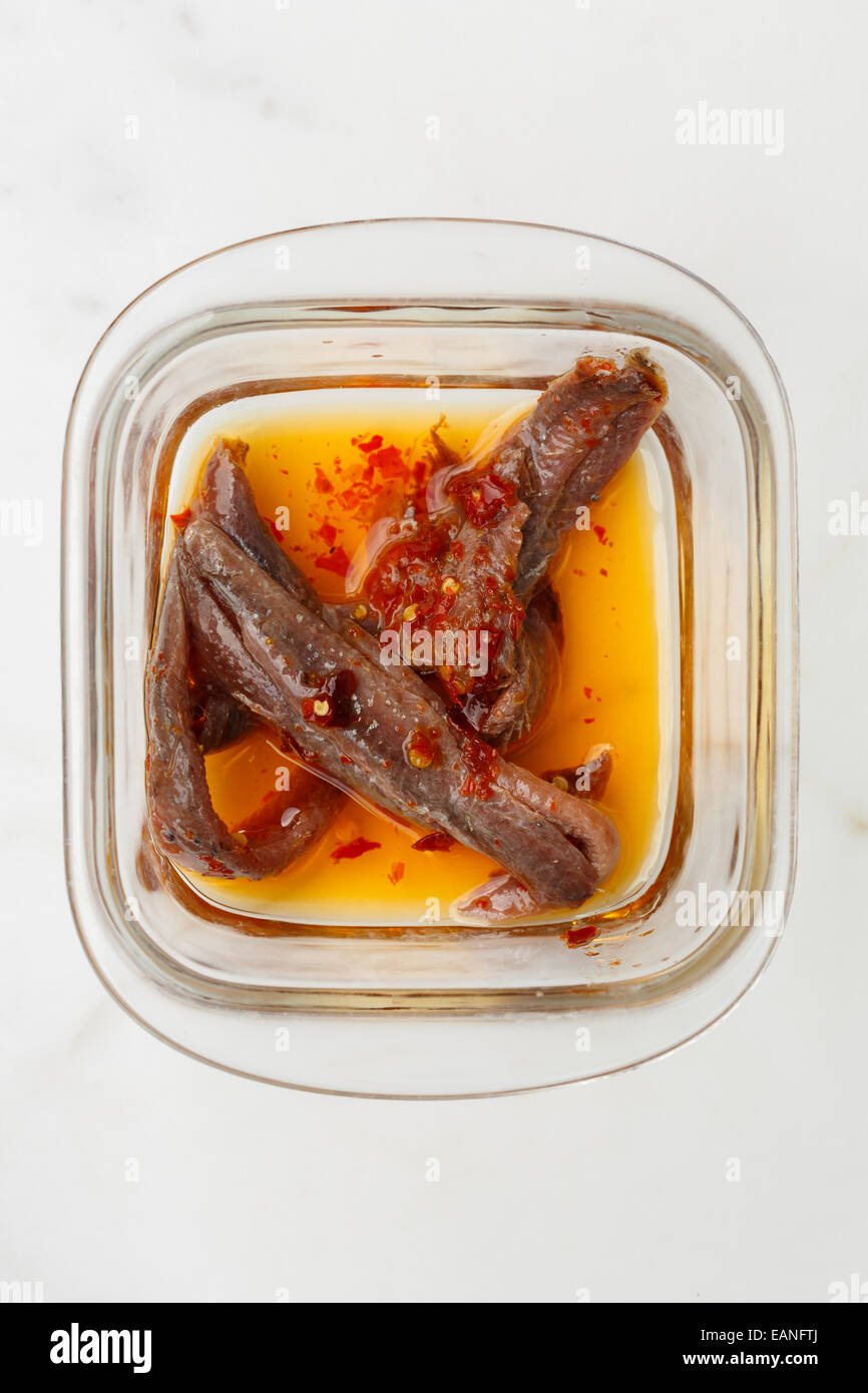 sicilian anchovies fillets with chilli pepper and oil in a glass bowl Stock Photo