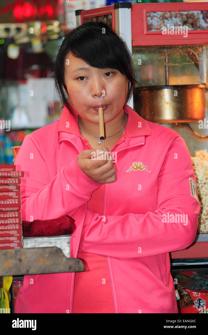 A Chinese woman in pink is playing Slide Whistle flute blowing woodwind musical instrument (Swanee whistle), piston flute. Stock Photo
