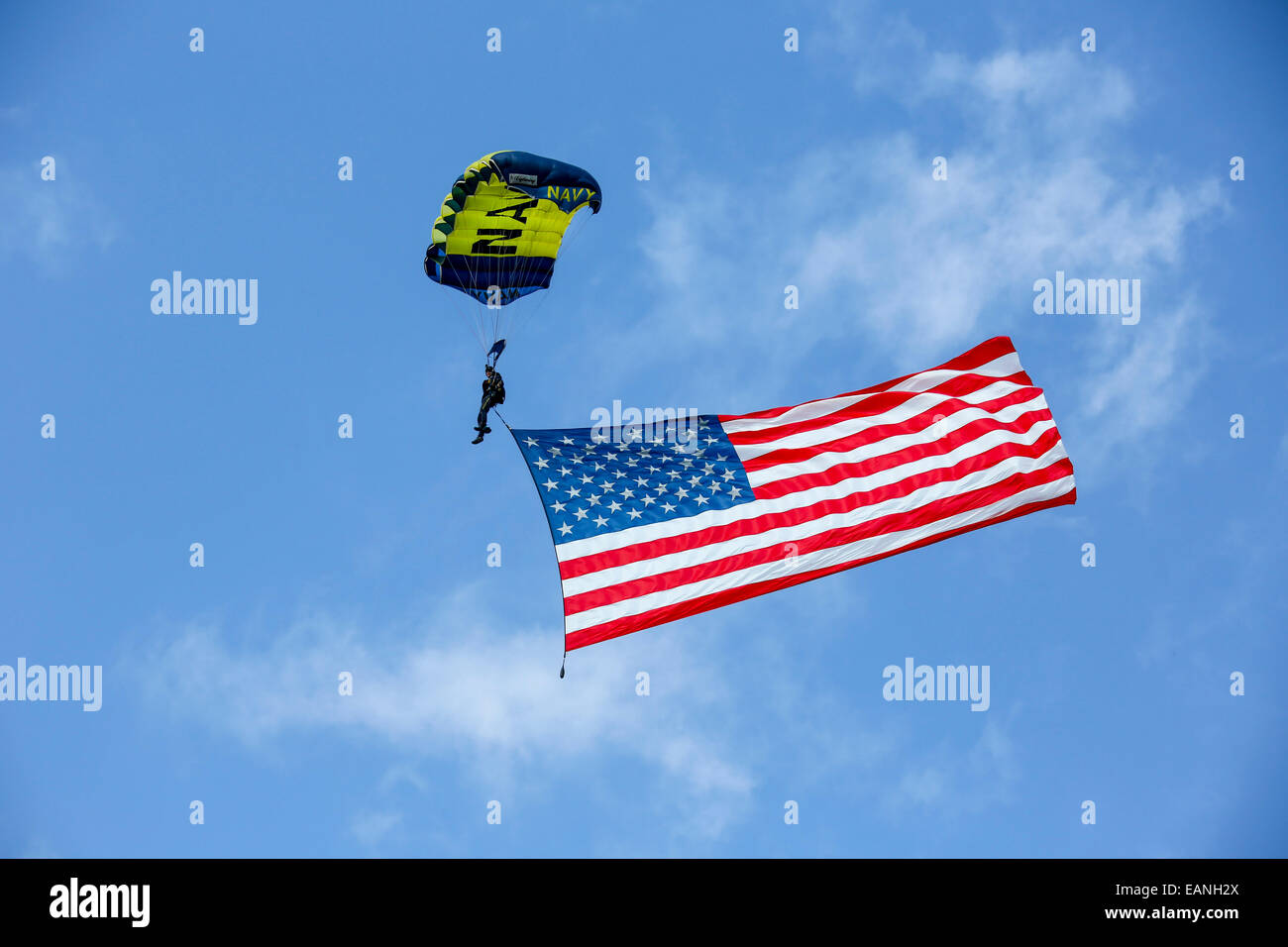 Member of the U.S. Navy Parachute Team, the Leap Frogs, flies the American Flag as he prepares to land at the demonstration grou Stock Photo