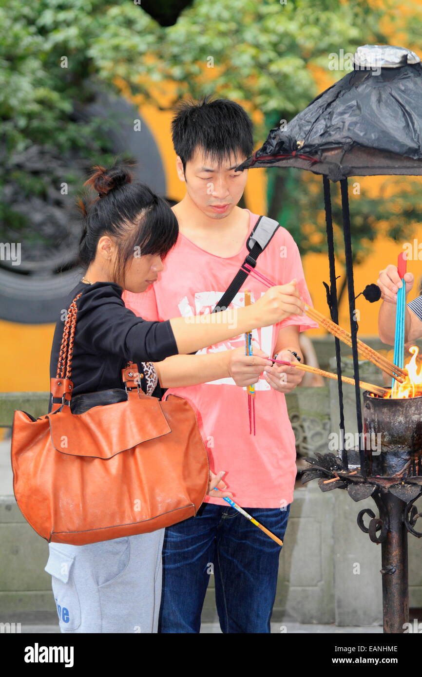 Young adult Chinese couple girl & boy firing with fire incenses in Buddhist LingYin Temple, Hangzhou, China Stock Photo