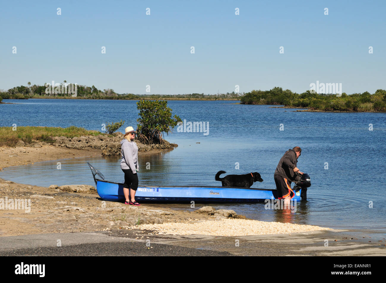 Man, woman and dog prepare to go fishing in a small boat Stock Photo