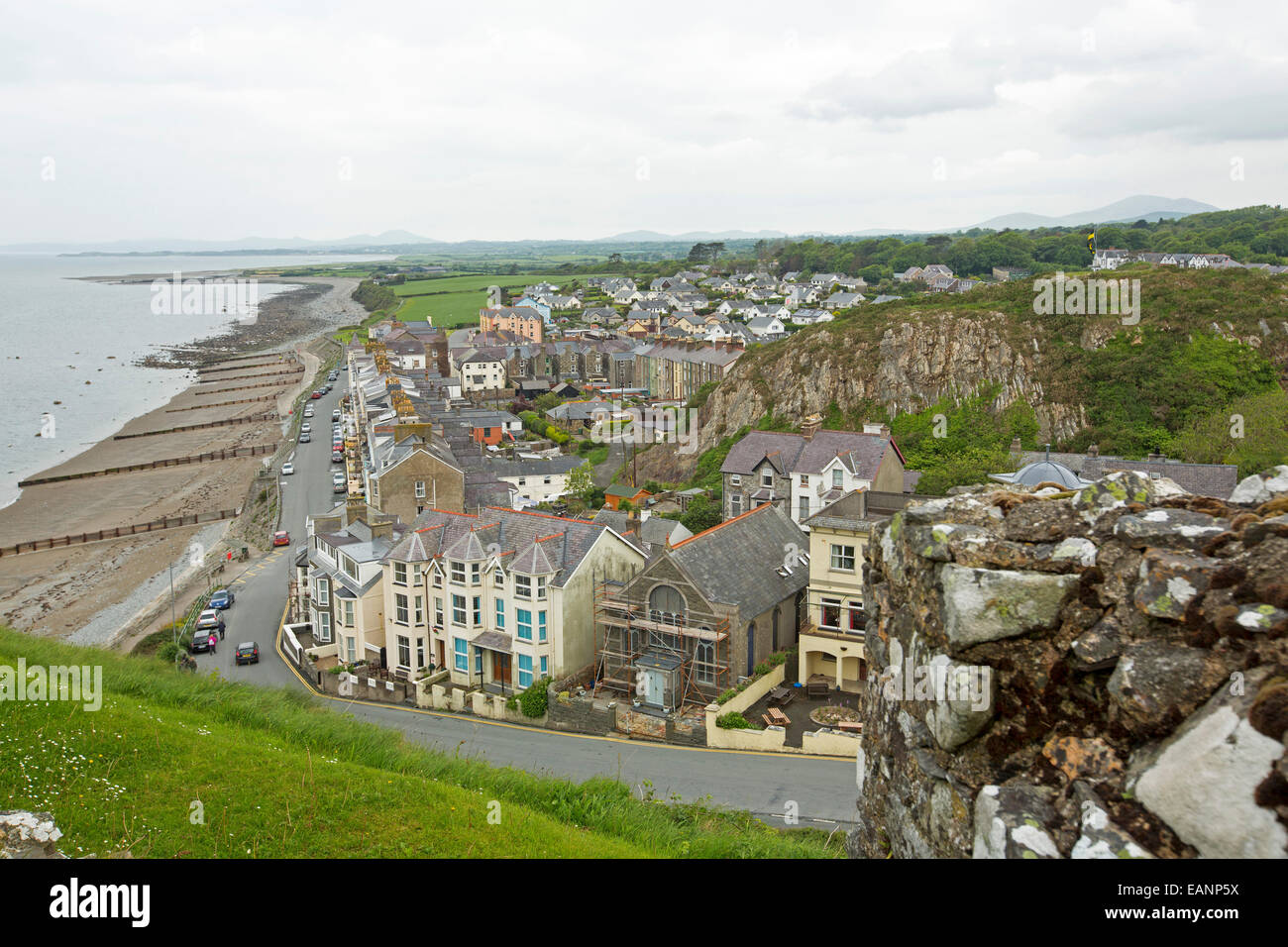 View, from hilltop castle, of historic Welsh town of Criccieth with row of houses by road bordering sandy beach of Cardigan Bay Stock Photo