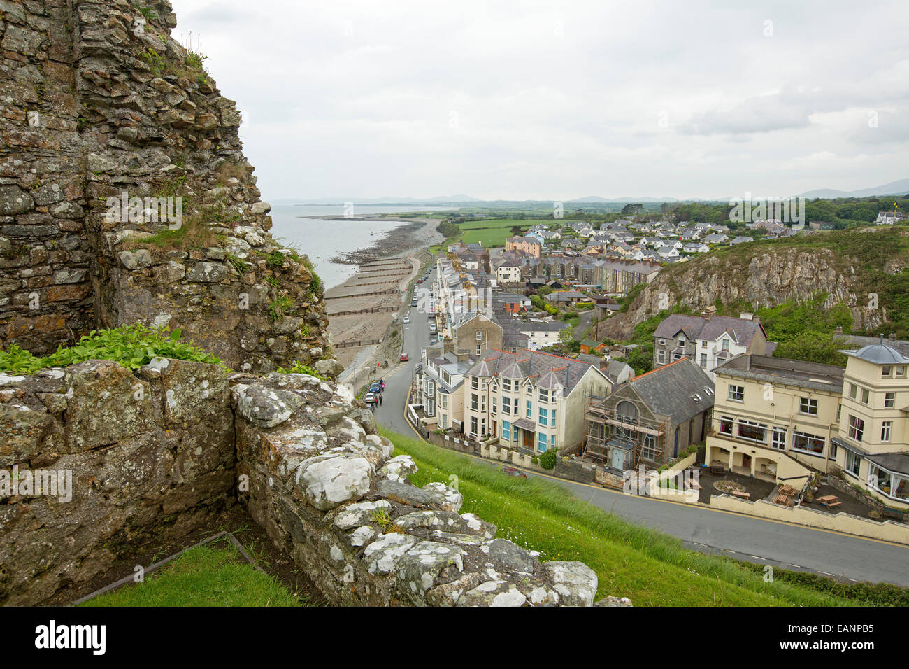 View, from hilltop castle, of historic Welsh town of Criccieth with row of houses by road bordering sandy beach of Cardigan Bay Stock Photo