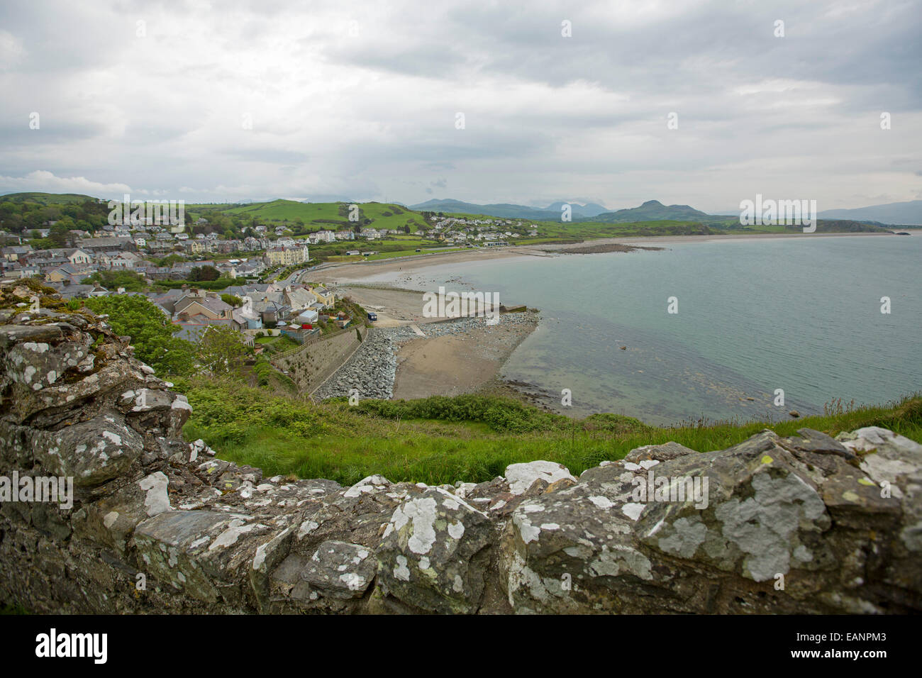 View, from hilltop castle, of Welsh town of Criccieth by beach of Cardigan Bay & green fields stretching to distant mountains Stock Photo