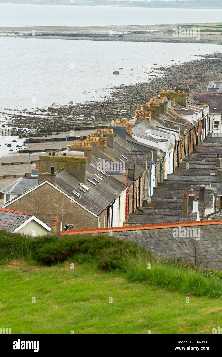 View, from hilltop castle, of historic Welsh town of Criccieth with row of houses by road bordering stony beach of Cardigan Bay Stock Photo