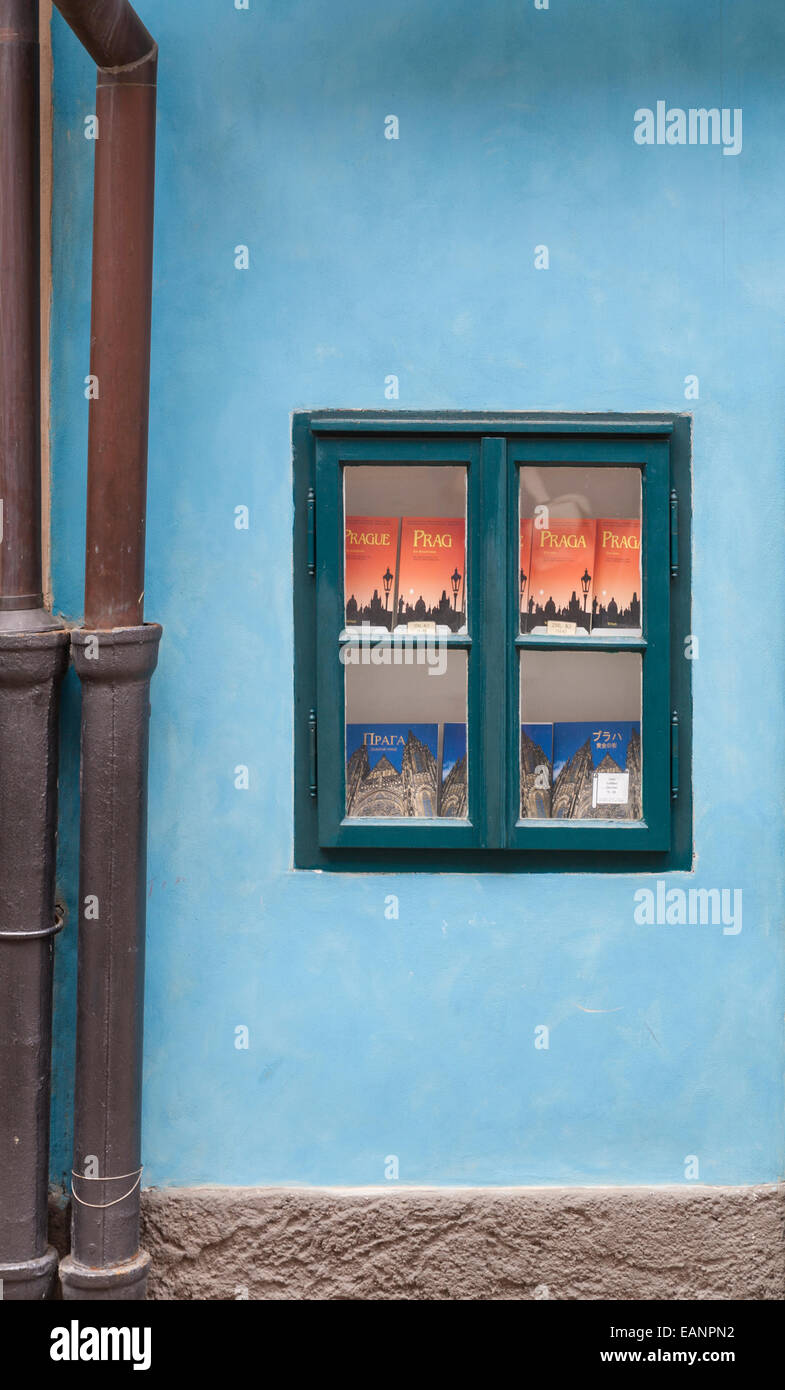 Green bookstore window set in blue stucco wall flanked by clay drain pipes on street in Prague Stock Photo