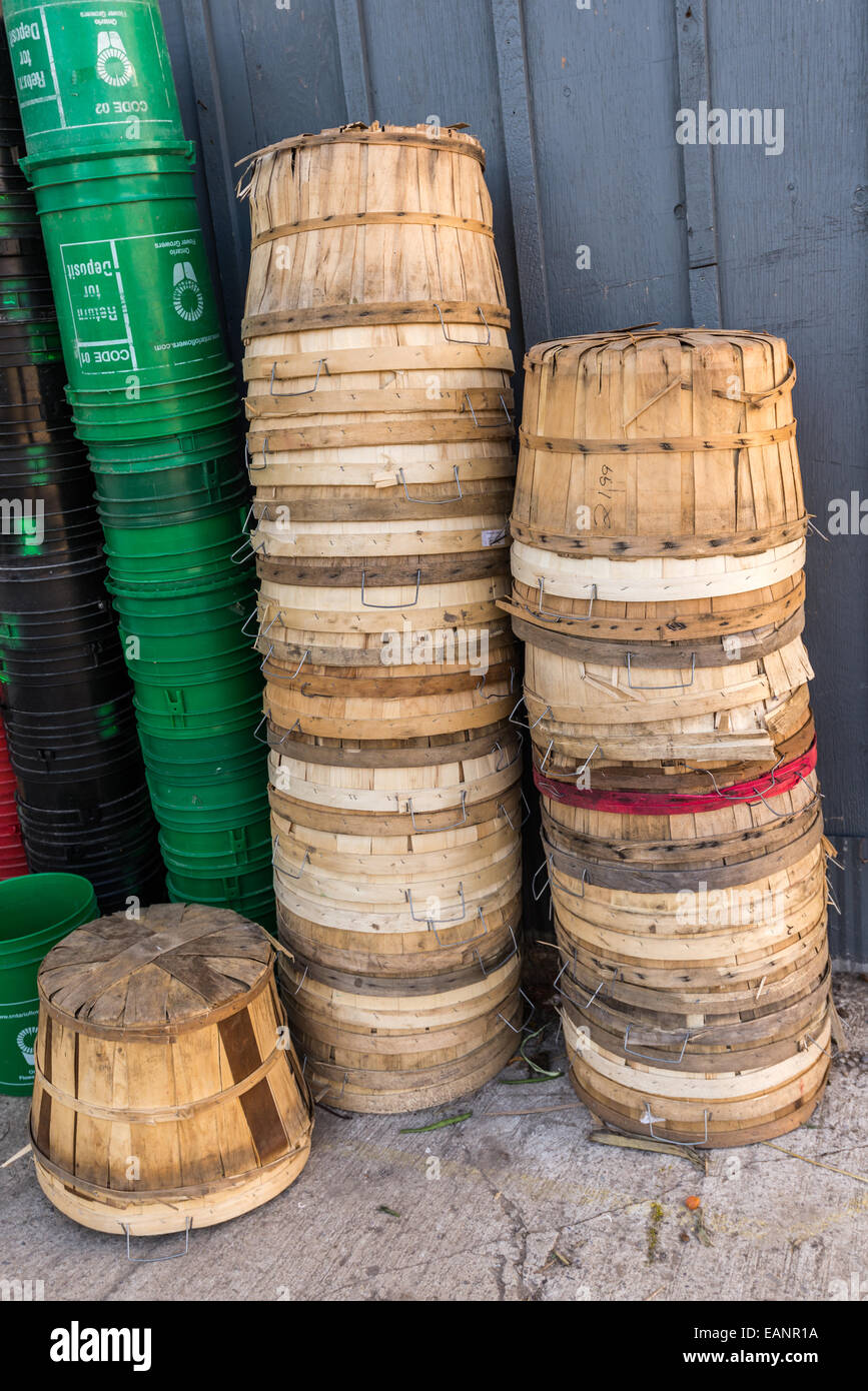 Empty wood bushel baskets and green plastic pails sit upside down