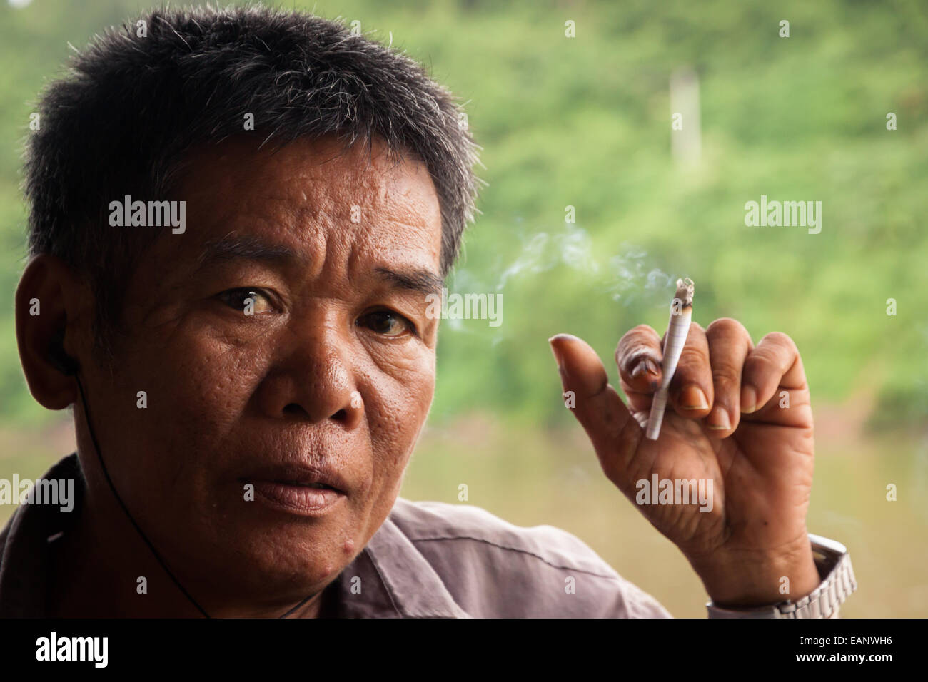 Lao man smoking a rolled cigarette Stock Photo