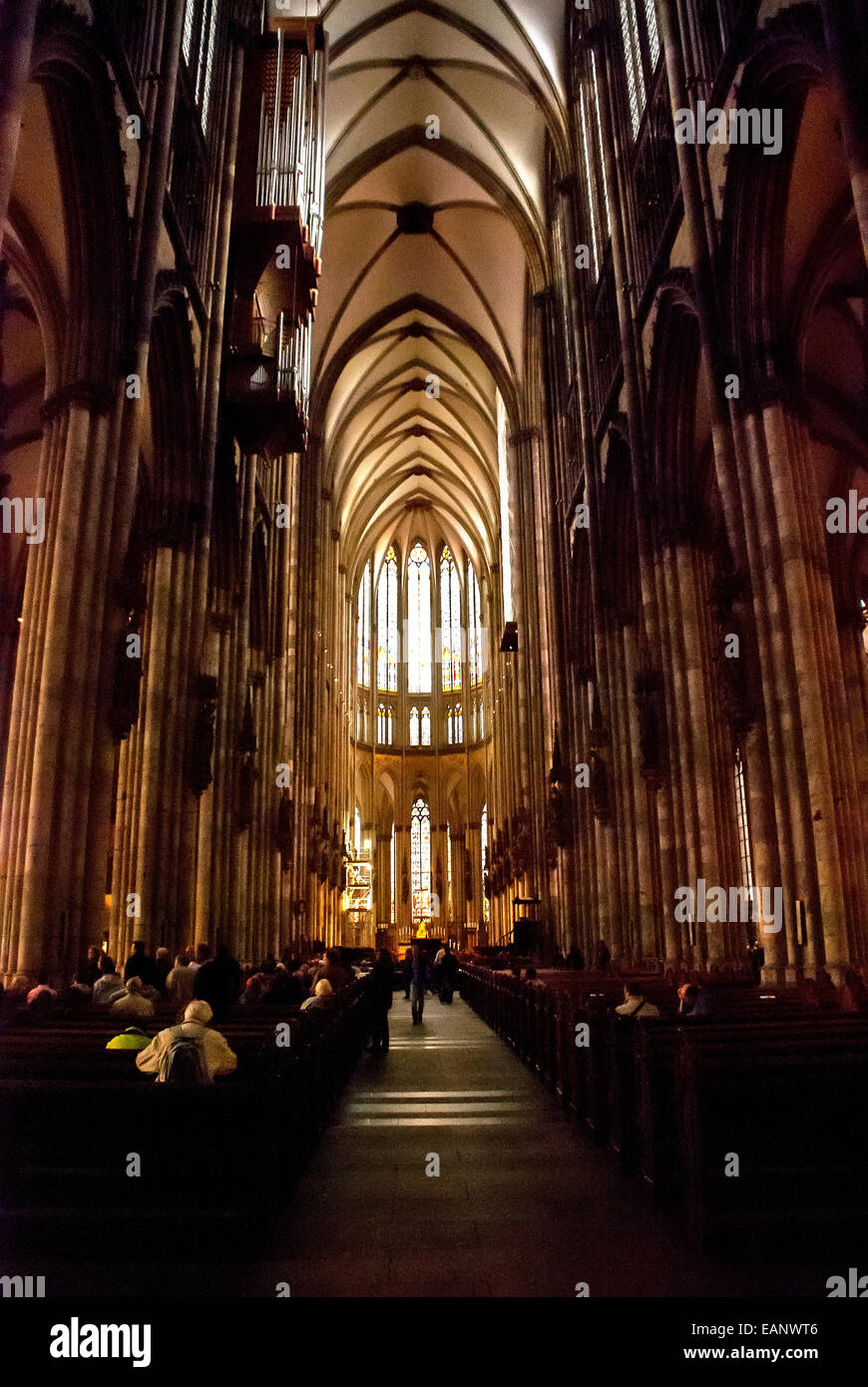 Pessoas sentadas rezando dentro da Catedral de Colônia. / People praying inside the Cologne Cathedral. Stock Photo