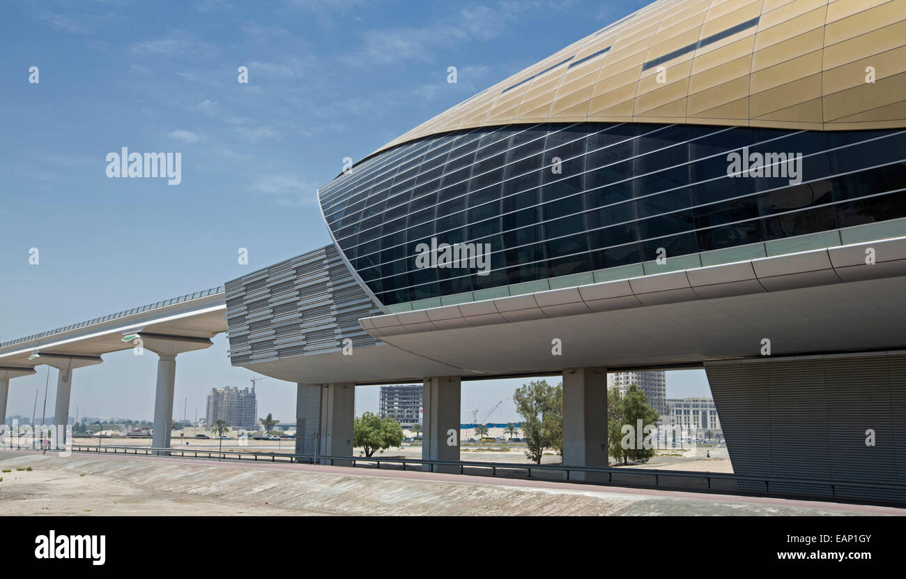 Unique futuristic building with unique curved design - metro / railway station with elevated railway track across desert at Dubai UAE under blue sky Stock Photo